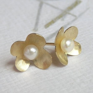 May include: A pair of gold flower-shaped earrings with a pearl in the center of each flower.