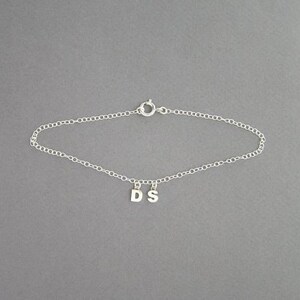May include: A silver chain bracelet with a charm that says "DS".