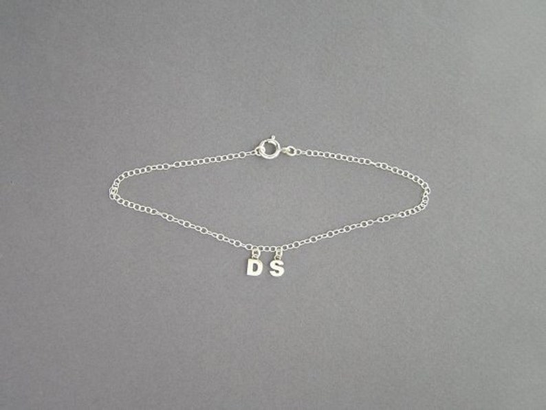 May include: A silver chain bracelet with a charm that says "DS".