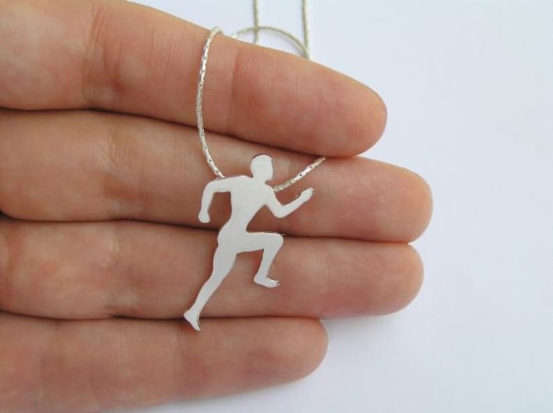 May include: Silver necklace with a runner pendant. The pendant is a silhouette of a person running.