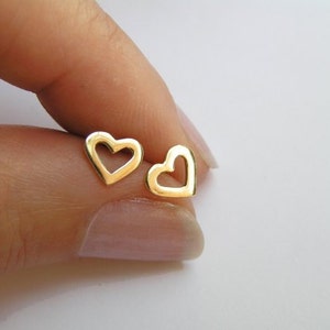 May include: A pair of gold heart-shaped earrings with a hollow center.