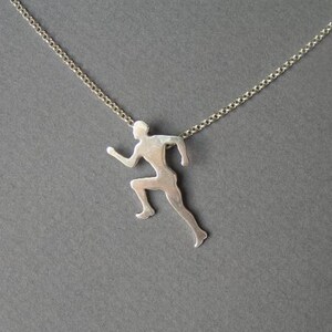 May include: A silver necklace with a pendant shaped like a running person.
