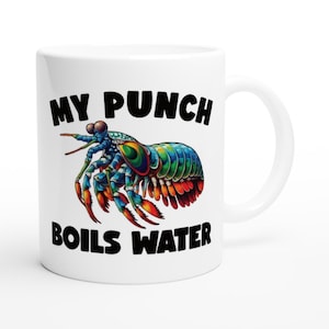 May include: White ceramic mug featuring a colorful illustration of a mantis shrimp with the text "MY PUNCH BOILS WATER" in black. The mantis shrimp is depicted in shades of blue, green, orange, and red. The mug has a standard handle.