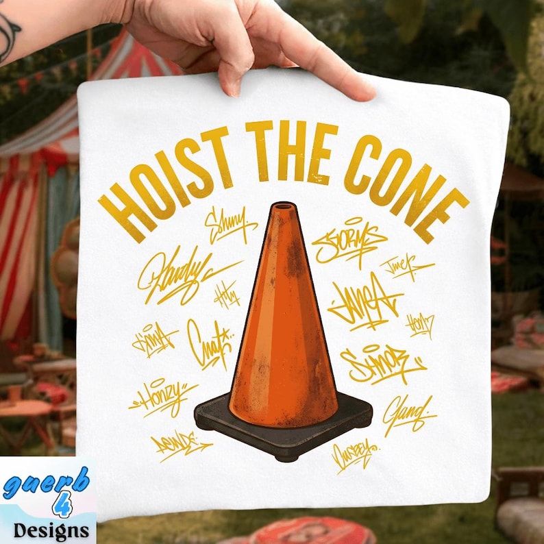 May include: White square pillow with the text "HOIST THE CONE" in gold lettering. An orange traffic cone is centered on the pillow, surrounded by gold signatures. The pillow has a black base and the brand name "guerb 4 Designs" in the bottom left corner.