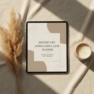 Puede incluir: Una tableta digital muestra un planificador titulado "Restart Life After Losing a Job Planner". La portada presenta formas geométricas beige y marrón con detalles dorados. Una vela encendida en un pequeño recipiente de cerámica beige está a la derecha, y hierba ornamental seca a la izquierda.