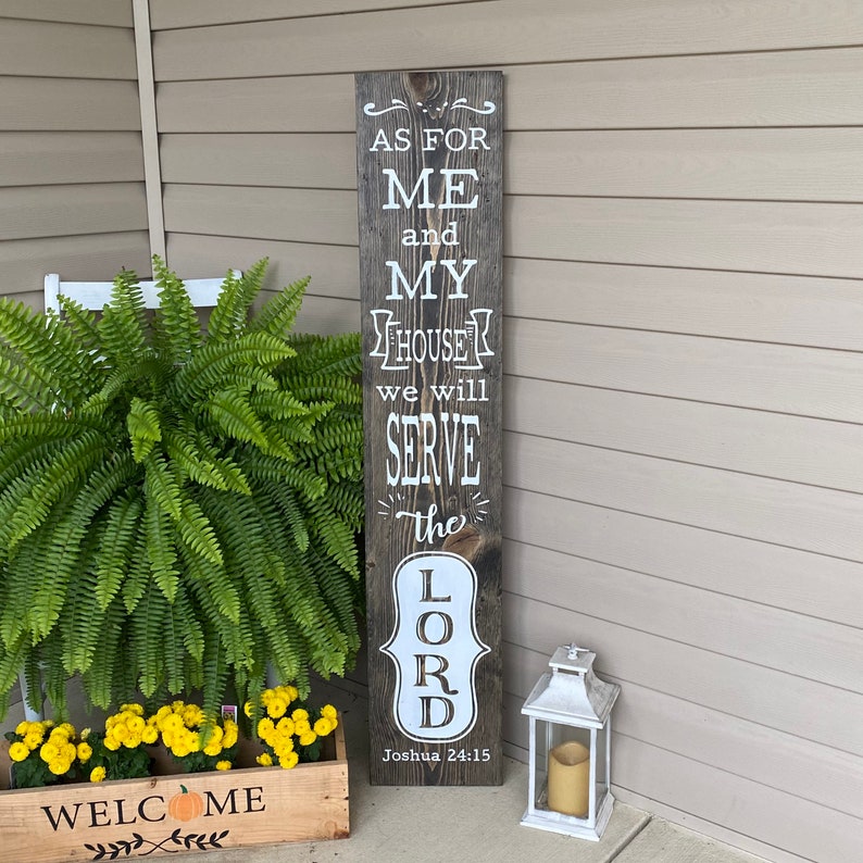 May include: A wooden sign with the text "As for me and my house we will serve the Lord, Joshua 24:15". The sign is painted in white on a dark brown wood background.