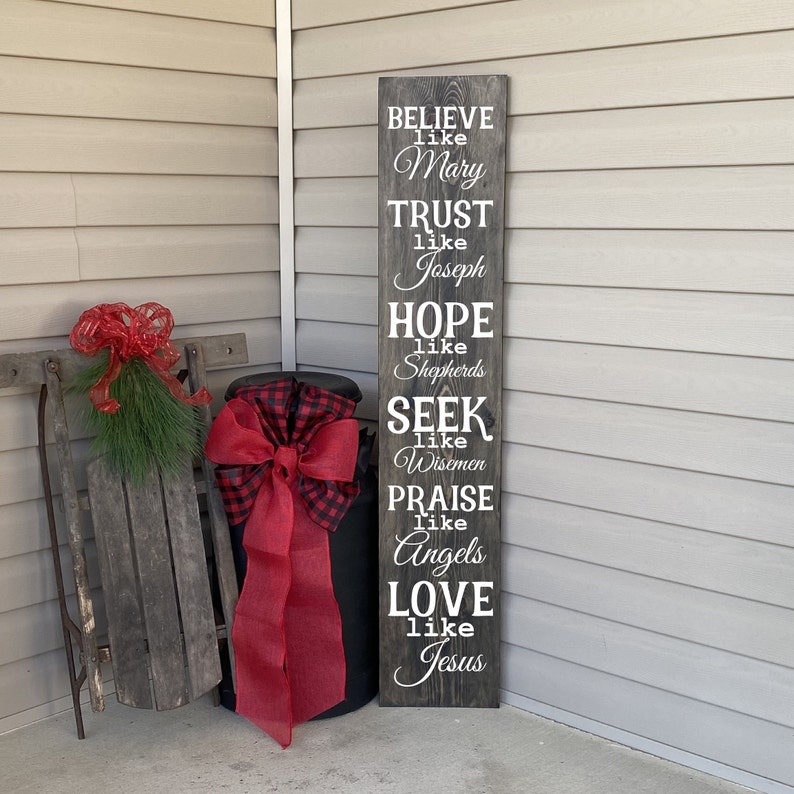 Op de afbeelding: Een houten bord met witte tekst die luidt: "BELIEVE like Mary, TRUST like Joseph, HOPE like Shepherds, SEEK like Wisemen, PRAISE like Angels, LOVE like Jesus".