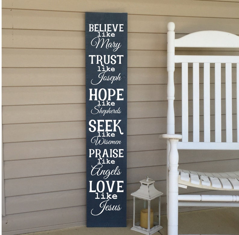 Op de afbeelding: Een donkerblauw houten bord met witte tekst die luidt: "BELIEVE like Mary, TRUST like Joseph, HOPE like Shepherds, SEEK like Wisemen, PRAISE like Angels, LOVE like Jesus".