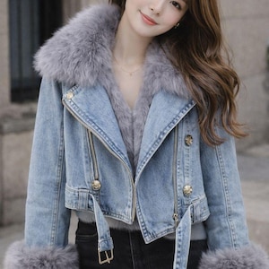 Peut inclure: Veste en jean bleu clair avec col et poignets en fausse fourrure grise. La veste est dotée d'une fermeture éclair, de boutons dorés et d'une ceinture à la taille. Un vêtement d'extérieur élégant.