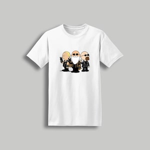 May include: White t-shirt featuring a cartoon illustration of three characters in black outfits and sunglasses. The characters are standing side by side, each holding a gun. The design is centered on the front of the shirt.