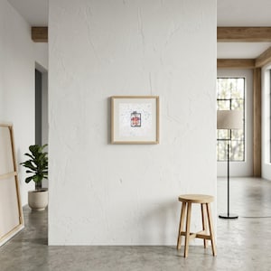 May include: A square framed wall art piece featuring a central rectangular illustration of a red and blue patterned garment, set against a white background with scattered blue and grey speckles, enclosed in a light-toned wooden frame.