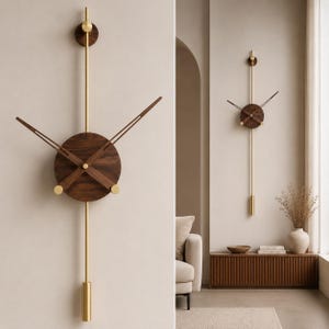 Könnte beinhalten: Eine moderne Wanduhr mit einem dunklen Holz-Zifferblatt und Zeigern, akzentuiert durch messingfarbene Details. Die Uhr hat ein langes, messingfarbenes Pendel und ein kreisförmiges Design. Sie ist an einer hellen Wand befestigt und schafft eine minimalistische Ästhetik.
