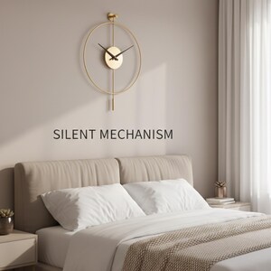K&ouml;nnte beinhalten: Eine goldfarbene, minimalistische Wanduhr mit kreisf&ouml;rmigem Rahmen und Pendel. Die Uhr hat schwarze Zeiger und ein kleines, rundes Zifferblatt. Der Text "SILENT MECHANISM" steht darunter. Die Uhr h&auml;ngt &uuml;ber einem Bett mit wei&szlig;er Bettw&auml;sche und einer beigen Decke.