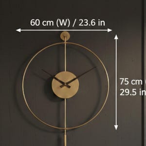 K&ouml;nnte beinhalten: Goldfarbene, minimalistische Wanduhr mit kreisf&ouml;rmigem Design. Das Zifferblatt ist rund, mit schwarzen Zeigern und einem Pendel. Die Uhr ist 60 cm breit und 75 cm hoch.