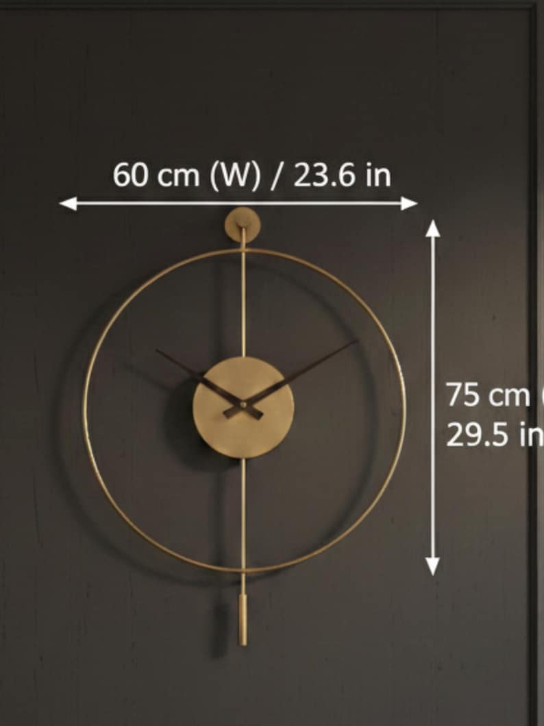K&ouml;nnte beinhalten: Goldfarbene, minimalistische Wanduhr mit kreisf&ouml;rmigem Design. Das Zifferblatt ist rund, mit schwarzen Zeigern und einem Pendel. Die Uhr ist 60 cm breit und 75 cm hoch.