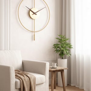 K&ouml;nnte beinhalten: Eine goldfarbene, minimalistische Wanduhr mit kreisf&ouml;rmigem Rahmen und Pendel. Das Zifferblatt ist hellbeige mit schwarzen Zeigern. Die Uhr ist an einer wei&szlig;en Wand befestigt. Der Raum verf&uuml;gt au&szlig;erdem &uuml;ber einen wei&szlig;en Sessel, einen Beistelltisch aus Holz und eine Topfpflanze.