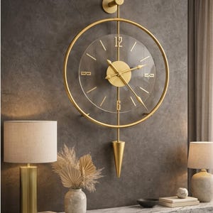 Pode incluir: Um relógio de parede dourado com um mostrador de vidro transparente e ponteiros dourados. O relógio tem um design circular com um pêndulo. O relógio está montado numa parede cinza escuro. Decoração de casa.