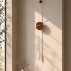 Peut inclure: Une horloge murale à pendule dotée d'un cadran circulaire en bois foncé avec de fines aiguilles en métal doré. Une longue tige métallique dorée s'étend verticalement vers le haut et le bas, se terminant par un poids cylindrique doré.