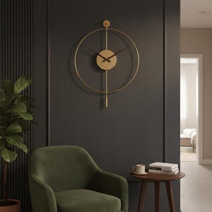 K&ouml;nnte beinhalten: Eine goldfarbene, minimalistische Wanduhr mit kreisf&ouml;rmigem Design und schwarzen Zeigern h&auml;ngt an einer dunkelgrauen Wand. Ein olivgr&uuml;ner Sessel und ein kleiner Beistelltisch aus Holz mit einer Tasse und B&uuml;chern vervollst&auml;ndigen die Szene. Der Durchmesser der Uhr betr&auml;gt ca. 61 cm.