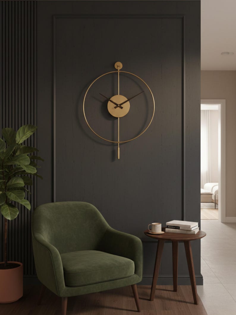 K&ouml;nnte beinhalten: Eine goldfarbene, minimalistische Wanduhr mit kreisf&ouml;rmigem Design und schwarzen Zeigern h&auml;ngt an einer dunkelgrauen Wand. Ein olivgr&uuml;ner Sessel und ein kleiner Beistelltisch aus Holz mit einer Tasse und B&uuml;chern vervollst&auml;ndigen die Szene. Der Durchmesser der Uhr betr&auml;gt ca. 61 cm.
