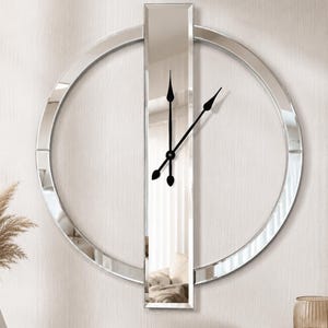 Puede incluir: Un reloj de pared moderno con una esfera de espejo y un marco circular de espejo. El reloj tiene manecillas negras y un centro rectangular de espejo. El diseño es minimalista y elegante, adecuado para la decoración del hogar.