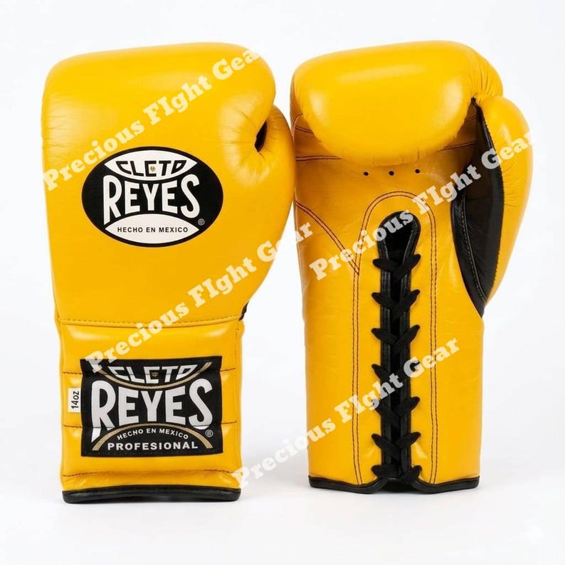 May include: A pair of bright yellow boxing gloves with black lace-up closures and black trim. The gloves feature the Cleto Reyes logo in black and white on the cuff and back of the hand, with a small white tag indicating 14oz weight.