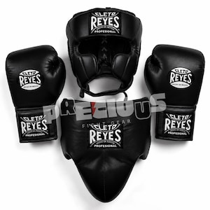 Peut inclure: Un ensemble d'équipement de boxe noir comprenant deux gants de boxe, un casque et une coquille de protection. Chaque pièce arbore le logo blanc Cleto Reyes avec le texte Hecho en Mexico Profesional. L'équipement est disposé symétriquement.