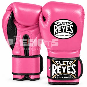 Peut inclure: Une paire de gants de boxe rose vif avec des bordures et des accents noirs. Les gants présentent le logo Cleto Reyes dans un ovale noir sur le dos de la main et sur la sangle du poignet. La sangle comprend une petite étiquette blanche marquée 12oz.