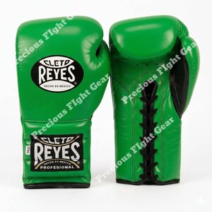May include: A pair of bright green boxing gloves featuring black lace-up closures and black trim. The gloves display the Cleto Reyes logo in a black oval patch on the front, with a secondary label indicating 14oz weight and professional status.