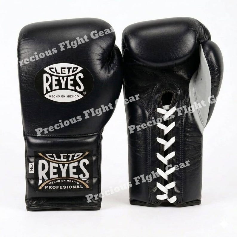 May include: A pair of black Cleto Reyes boxing gloves with white laces. The gloves feature the Cleto Reyes logo and the text 'HECHO EN MEXICO' and 'PROFESIONAL'. A small tag on the wrist indicates a weight of 14oz for these professional gloves.