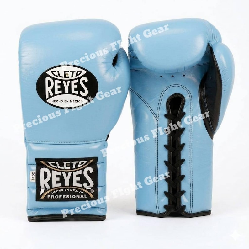 May include: A pair of light blue Cleto Reyes boxing gloves with black lace-up closures and black trim. The gloves feature the Cleto Reyes logo in an oval patch and a rectangular label indicating 14oz weight and Hecho en Mexico branding.