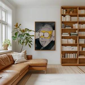 May include: A framed artwork depicting Albert Einstein in black and white, with a yellow cartoon eye mask. The artwork hangs in a living room with a brown leather sofa, a wooden bookcase, and a large window.