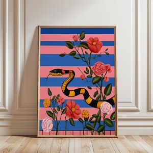 May include: Art print in a wooden frame, depicting a snake with black and yellow markings, on a pink and blue striped backdrop. The image includes red and pink flowers and green leaves, offering a colourful and decorative design.