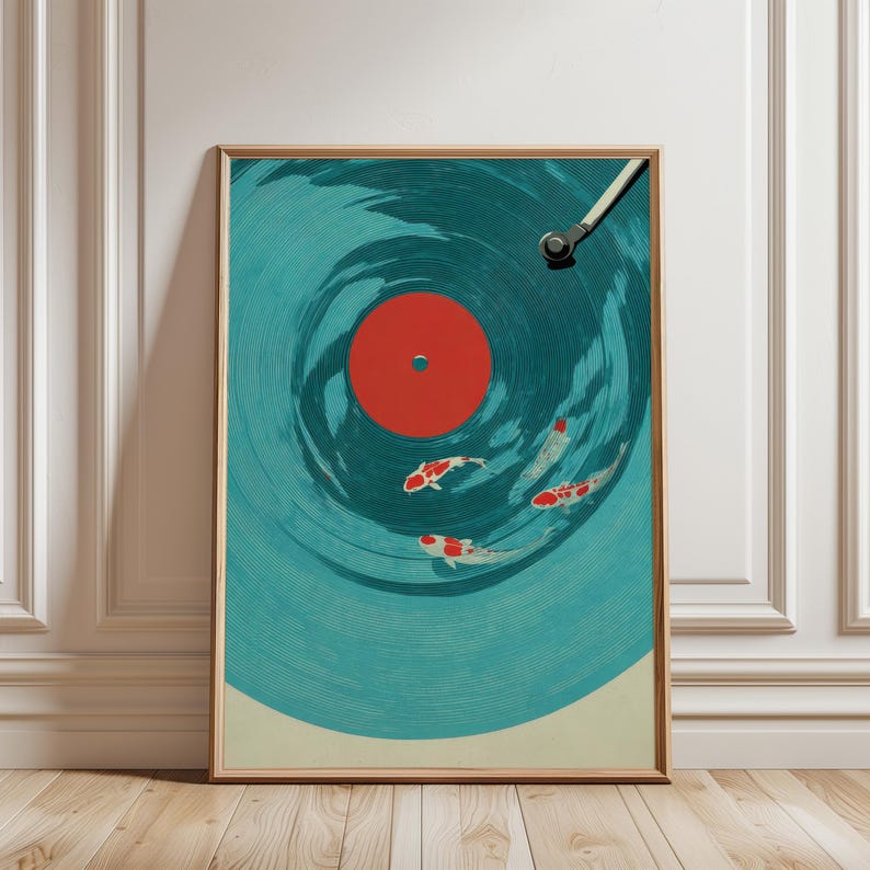 Op de afbeelding: Ingelijste kunstdruk met een gestileerd ontwerp van een vinylplaat met koi-vissen die in de groeven zwemmen. De plaat is turquoise met een rode kern, en de koi zijn wit met rode markeringen. Het kunstwerk zit in een houten lijst.