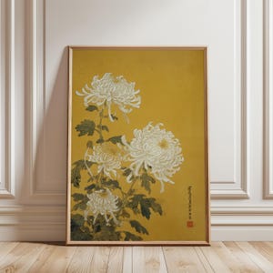 May include: A framed print featuring a botanical illustration of white chrysanthemums against a mustard yellow background. The flowers have layered petals and green leaves. The artwork is in a wooden frame.