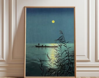 May include: A framed print of a moonlit lake scene. A boat with several figures is on the water, with tall reeds in the foreground. The moon is a bright yellow circle in the dark blue sky. The water reflects the moonlight.
