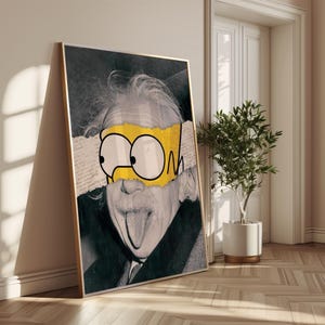 May include: Framed art print depicting Albert Einstein in black and white, overlaid with a yellow and white cartoon element. The artwork leans against a wall, with a small potted plant and a door visible in the background.