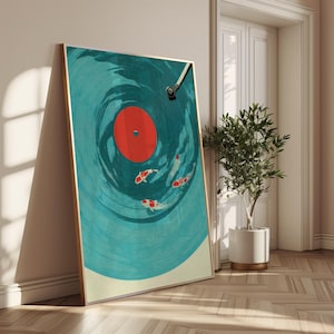 Op de afbeelding: Een ingelijste kunstdruk met een ontwerp van een turquoise vinylplaat met een rode kern en koi-karpers die in de groeven zwemmen. Het kunstwerk heeft een gouden lijst en leunt tegen een muur.