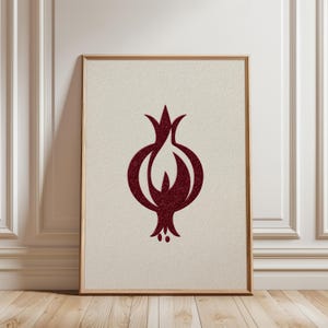 May include: Framed art print featuring a stylized pomegranate design in a deep burgundy color. The artwork is set against a textured, off-white background and framed in a natural wood tone. The pomegranate illustration has a textured appearance.