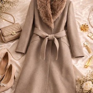 Peut inclure: Un long manteau beige avec un col en fausse fourrure et une ceinture assortie nou&eacute;e &agrave; la taille. Le manteau est pr&eacute;sent&eacute; avec un sac &agrave; main beige, des chaussures &agrave; talons hauts et des &eacute;l&eacute;ments d&eacute;coratifs, sugg&eacute;rant un th&egrave;me de mode. La longueur du manteau est d'environ 130 cm.
