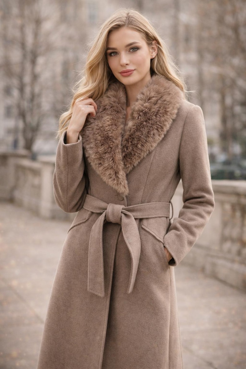 Peut inclure: Un long manteau marron clair avec un col en fausse fourrure et une ceinture assortie nou&eacute;e &agrave; la taille. Le manteau a un design classique avec une coupe ajust&eacute;e et des poches. Le mod&egrave;le porte le manteau &agrave; l'ext&eacute;rieur.