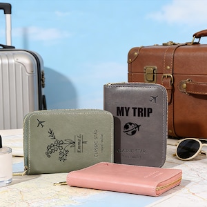 May include: A collection of travel wallets in various colors, including gray, green, and pink, with gold zippers. The wallets feature travel-themed graphics and text, such as airplanes and the words "MY TRIP" and "CLASSIC STAR travel wallet". A suitcase and sunglasses are in the background.