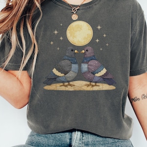 Może przedstawiać: Biały ceramiczny kubek z czarnym uchem i napisem "But First, Coffee" pogrubioną, czarną czcionką. Kubek jest ustawiony na rozmytym tle. Kubek ma około 10 cm wysokości.