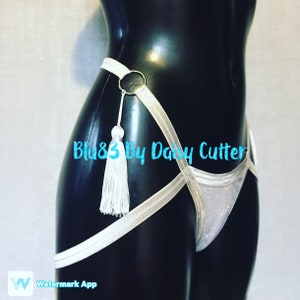May include: White lingerie with a silver glitter fabric and a white tassel. The lingerie has a silver strap design with a silver ring.