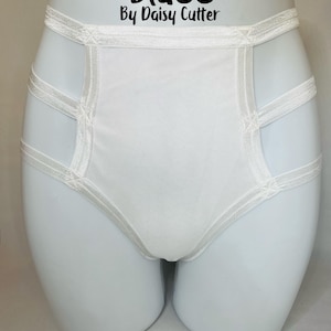 Puede incluir: Ropa interior blanca de talle alto con un diseño cruzado. La ropa interior tiene un ribete de encaje blanco y el texto "Blu83 By Daisy Cutter" está impreso en la cintura.