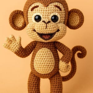 Puede incluir: Un juguete de mono de ganchillo hecho a mano en tonos marrón y beige. El mono tiene grandes ojos negros, una cara sonriente y está saludando con la mano izquierda. El juguete está de pie sobre dos pies y tiene una cola rizada. El mono mide unos 25 cm de alto.