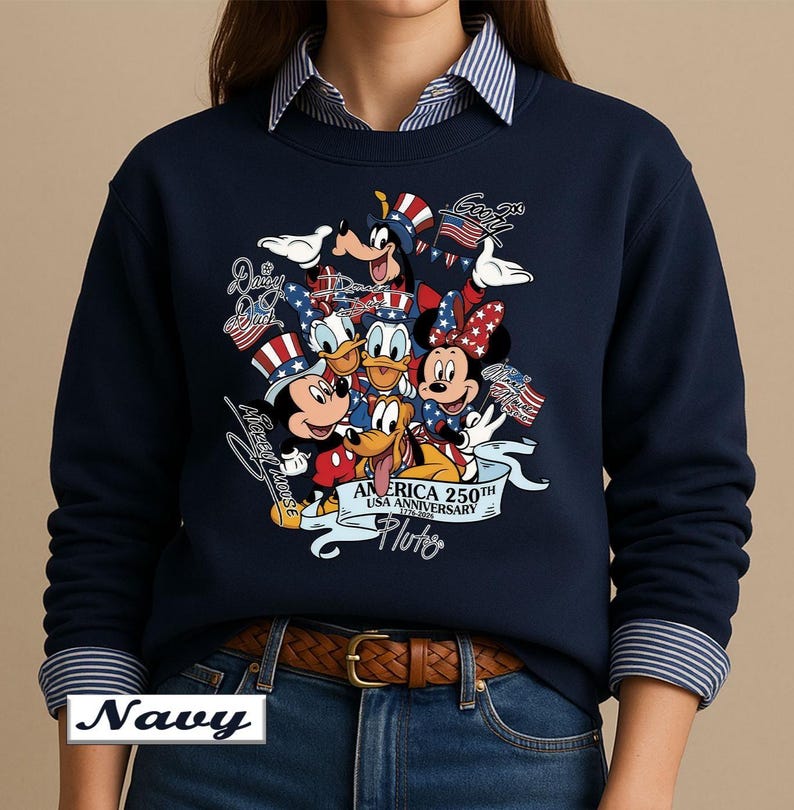 May include: A navy blue crewneck sweatshirt featuring a graphic print of Mickey Mouse, Minnie Mouse, Donald Duck, Daisy Duck, Goofy, and Pluto wearing patriotic hats. The text reads America 250th USA Anniversary 1776-2026 with character names.