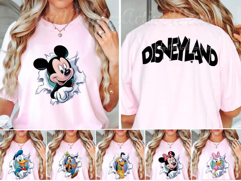 May include: A light pink t-shirt featuring a graphic of Mickey Mouse emerging from a torn paper effect on the front and the word Disneyland printed in large black letters across the upper back. The design includes various Disney character options.