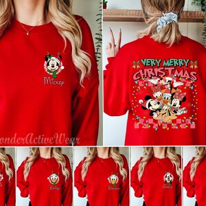 May include: A red long-sleeve sweatshirt featuring a small graphic of Mickey Mouse on the front left chest. The back displays a large graphic with the text "VERY MERRY CHRISTMAS" and a group of Disney characters including Mickey, Minnie, Donald, Daisy, Goofy, and Pluto.