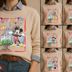 May include: A sand-colored crewneck sweatshirt featuring a graphic print with the text Disney Trip. The design includes a castle, a large tree, and various Disney characters like Mickey Mouse, Pluto, Goofy, Daisy Duck, Minnie Mouse, and Donald Duck.